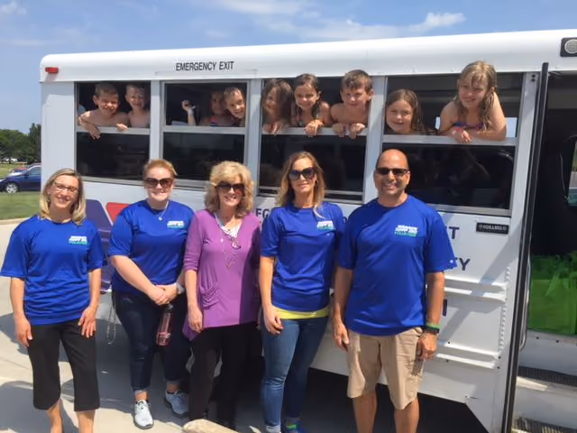 The Warren Rupp volunteers outside of a white school bus filled with children