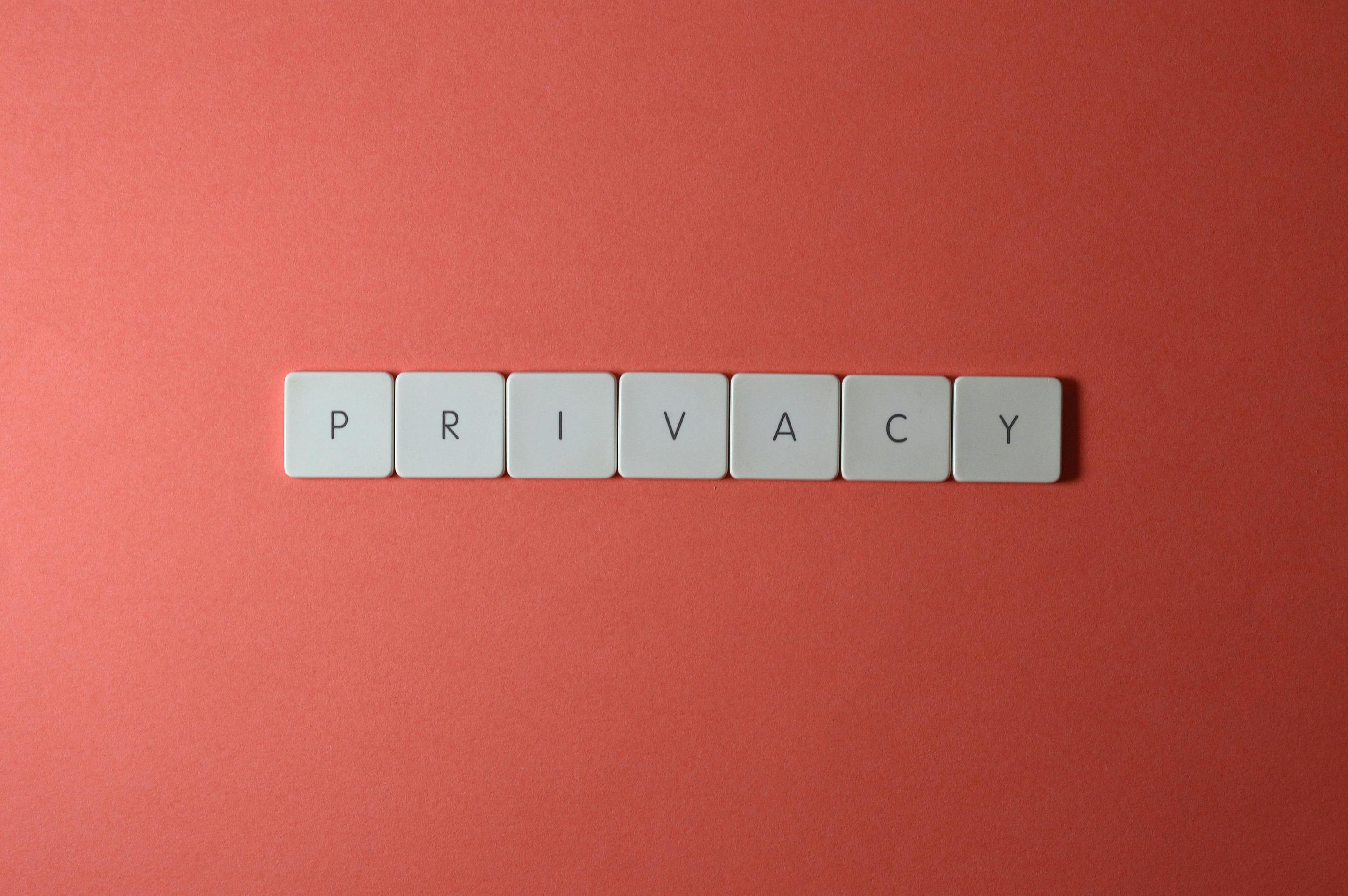 White letter tiles spelling the word PRIVACY on a coral background