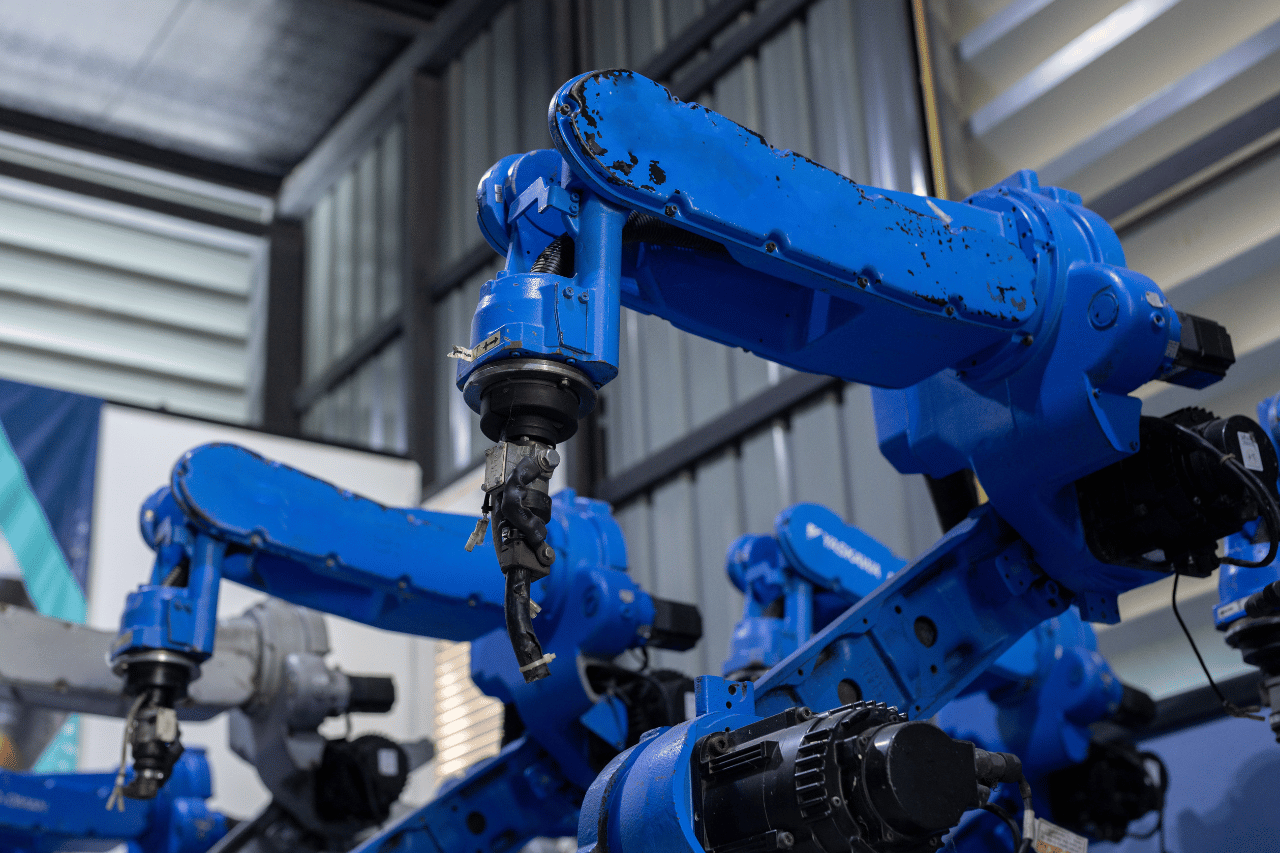 Several blue robotic arms stand ready on the assembly line in this brightly lit interior shot.