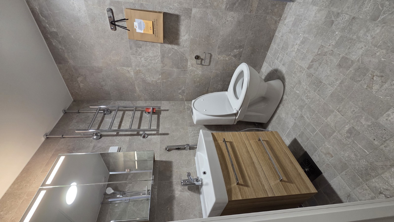 Linjasaneerauksessa uusittu kylpyhuone, jossa pesuallaskaappi ja wc-istuin.