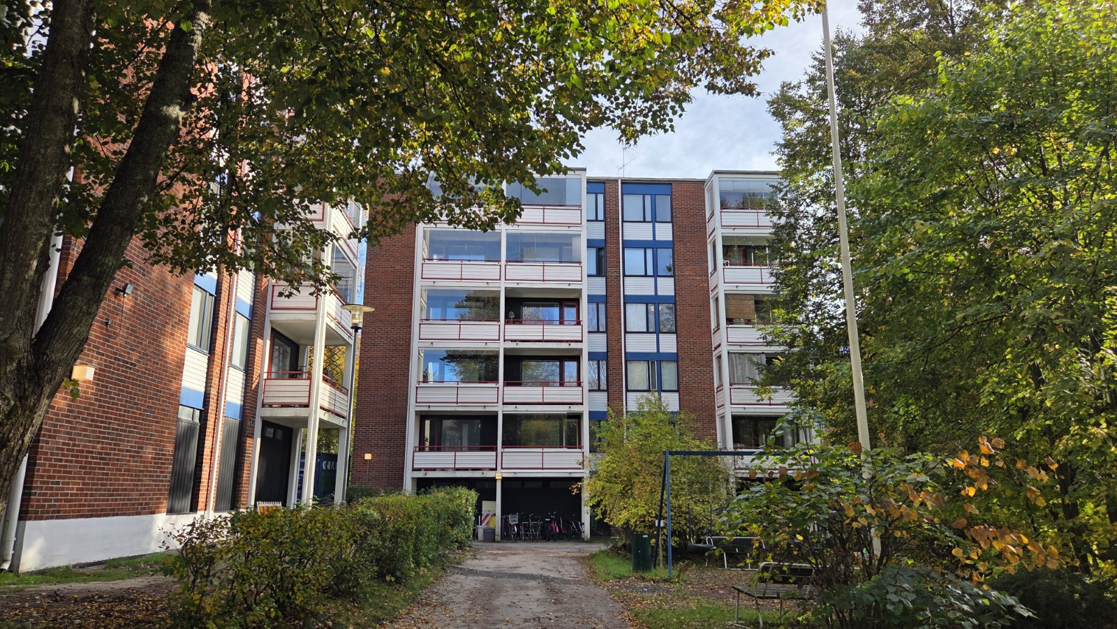 As Oy Vantaan Pähkinäniityn kerrostalo puiden lomasta kuvattuna.