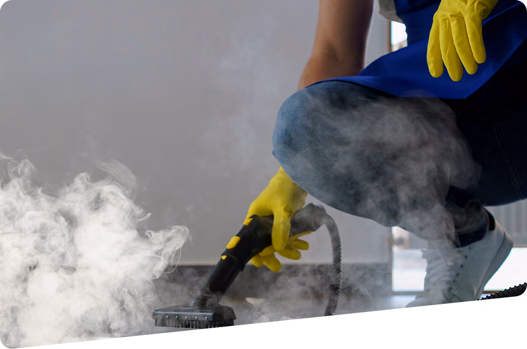 Bauendreinigung: Reinigungskraft in Arbeitskleidung reinigt den Boden mit einem speziellen Dampfreinigungsgerät.