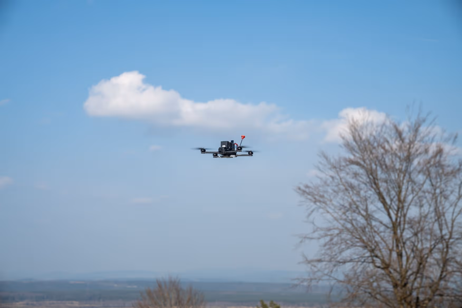 A small plane flying over a tree in a field.