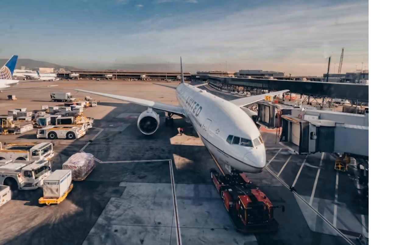United Airlines plane parked at gate G1 with airport ground vehicles and cargo nearby.