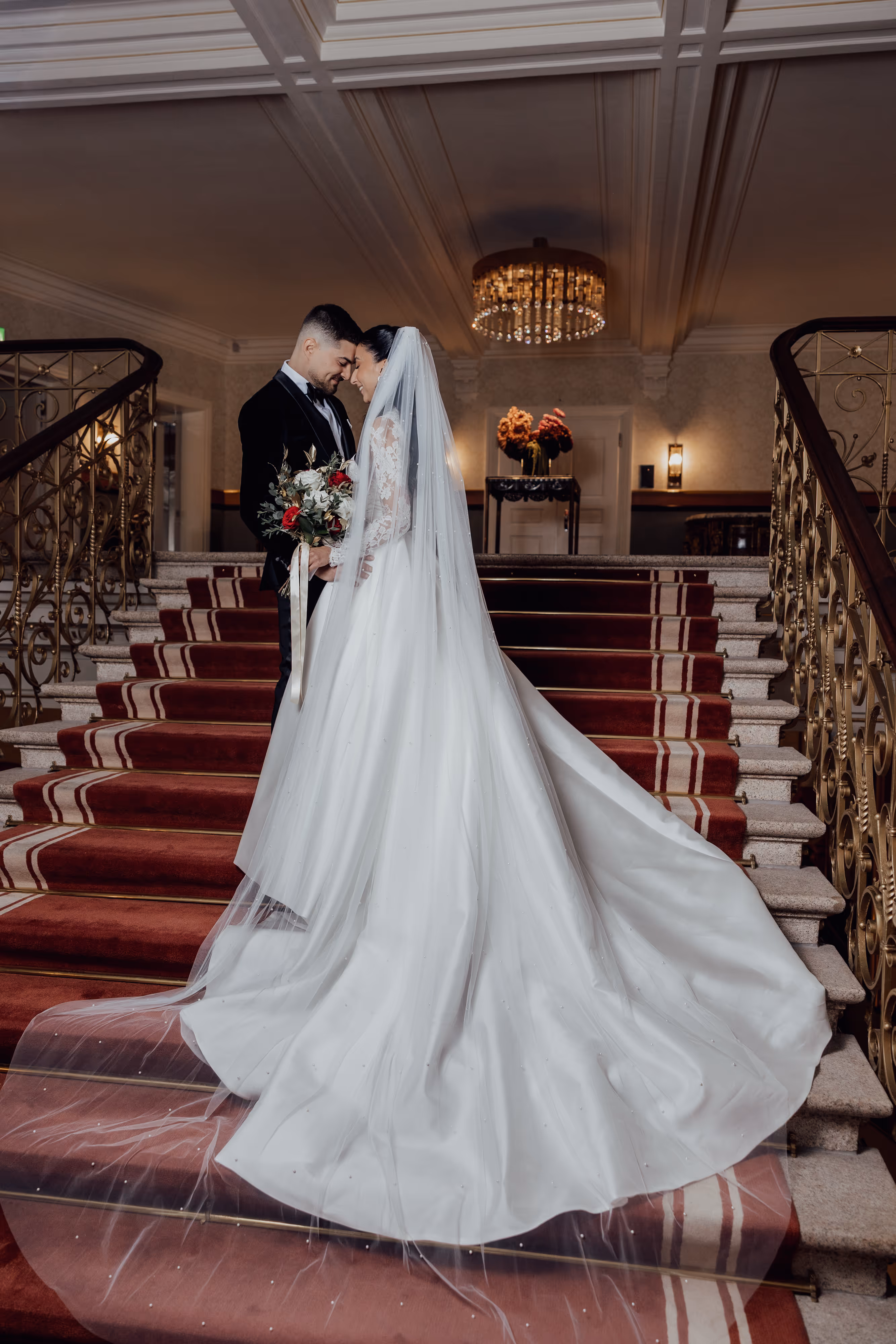 Brautpaar auf der roten Teppichtreppe im Dolder Grand Zürich mit Kronleuchter – Hochzeitsfotograf Lee Kramer