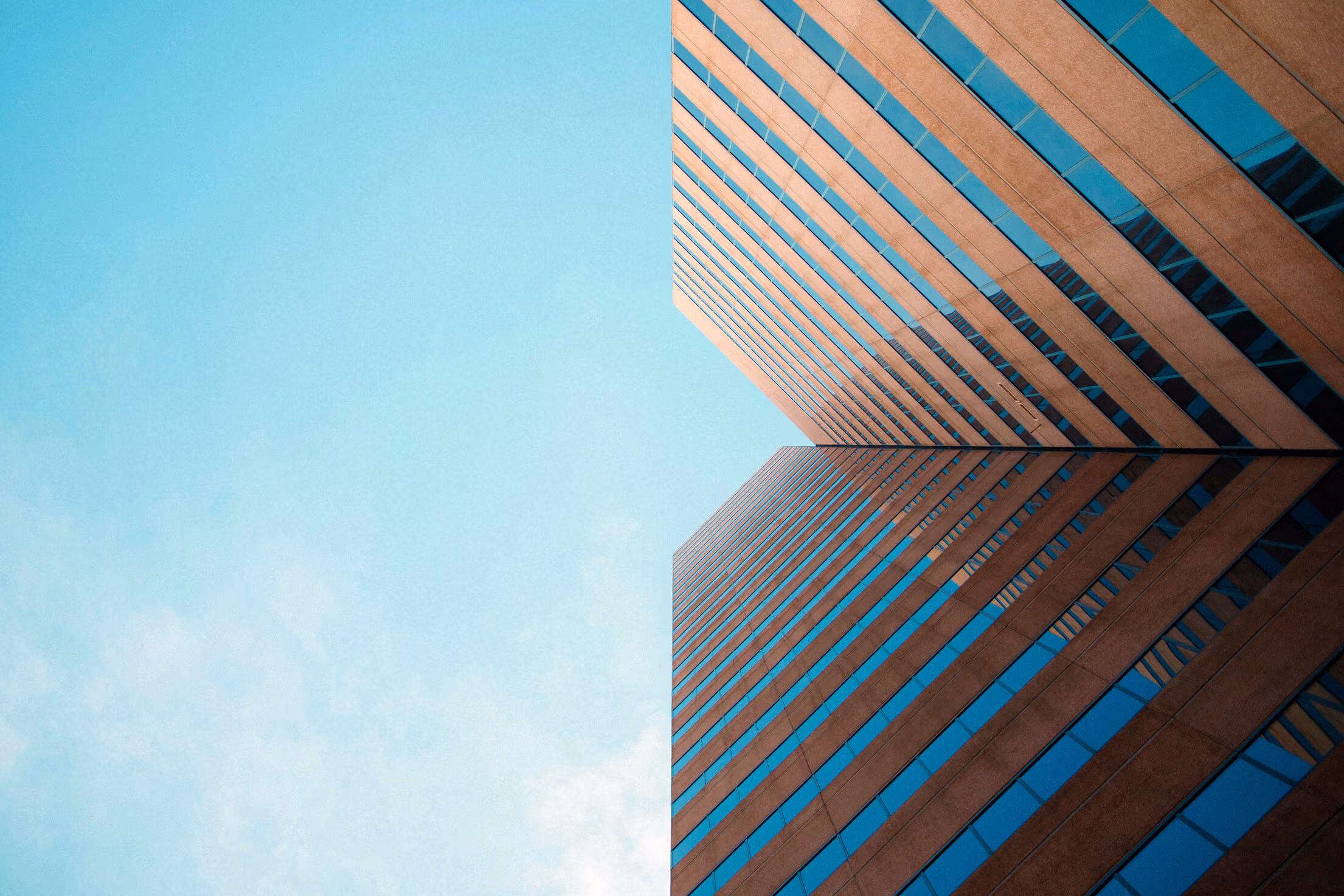Low angle of a large office building with a striking blue sky in the background.