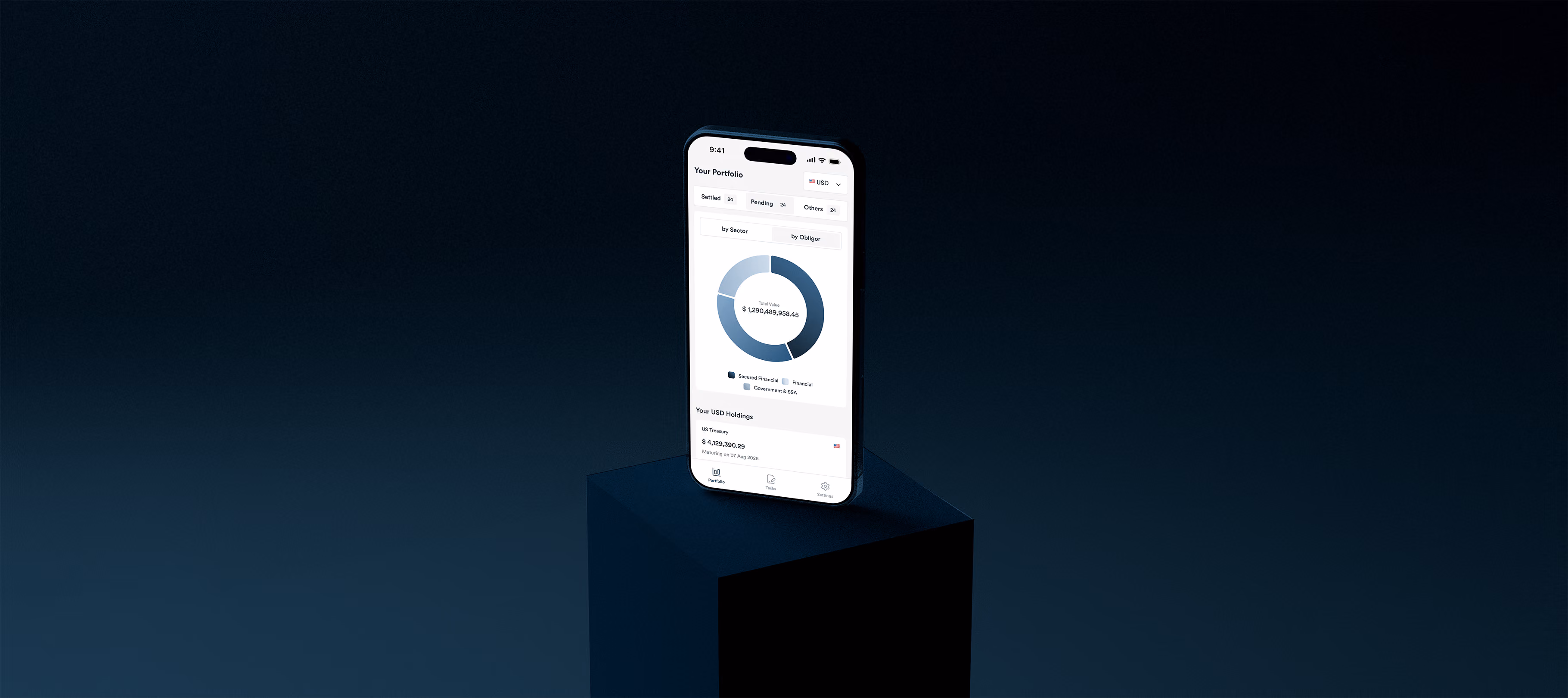 Smartphone showing financial portfolio app with pie chart and USD holdings on dark pedestal.