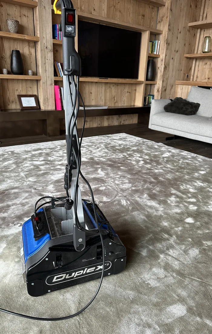 Machine de nettoyage professionnelle sur un grand tapis de salon, dans un chalet