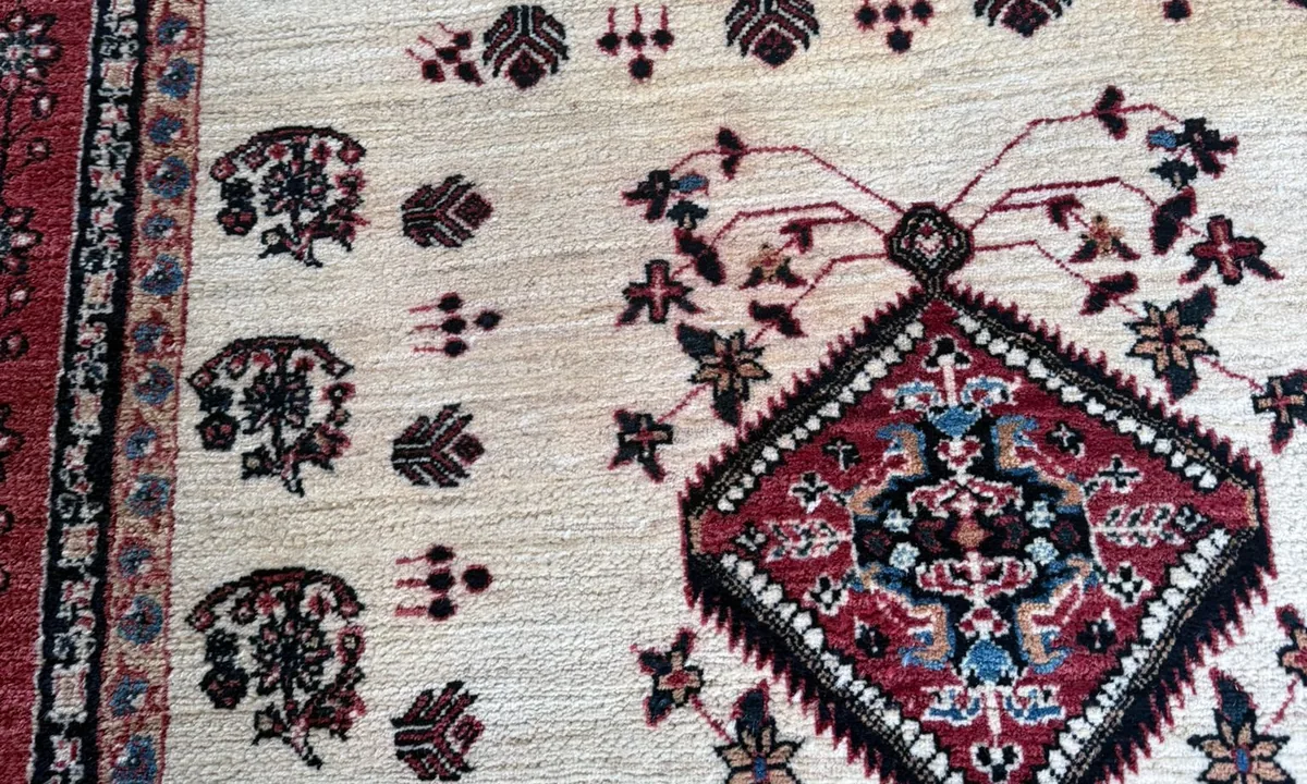 Tapis d'Orient en laine, motifs rouges et noirs sur fond crème, chez un client