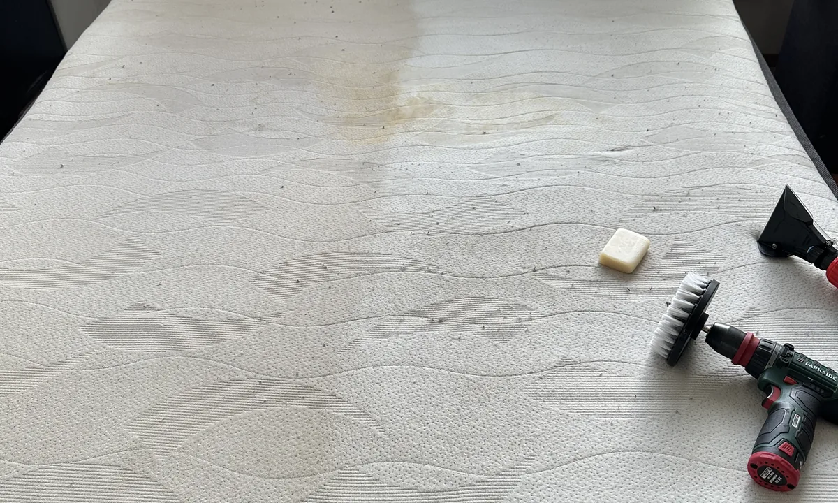Matelas taché, avec une brosse et un pain de savon, pendant le traitement des taches