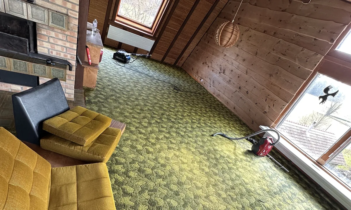 Pièce mansardée avec une moquette verte à motifs, chez un client
