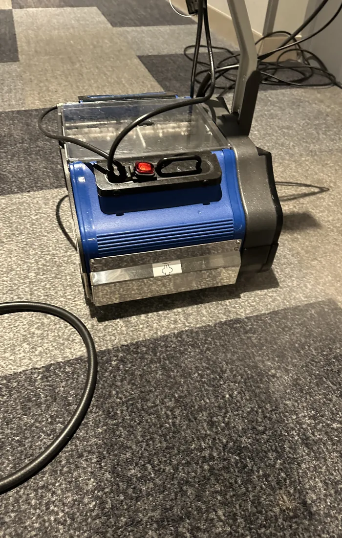 Machine professionnelle de nettoyage de moquette, posée sur une moquette en dalles