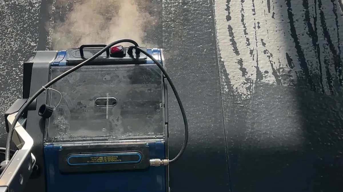 Machine à brosses rotatives et vapeur sur un tatami noir, pendant le nettoyage