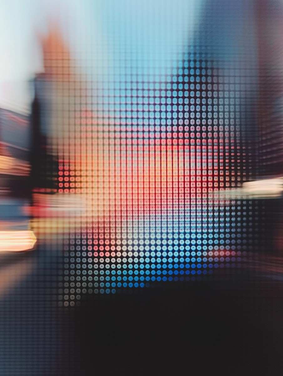Blurred cityscape behind a grid of small circular dots creating an abstract mosaic pattern.