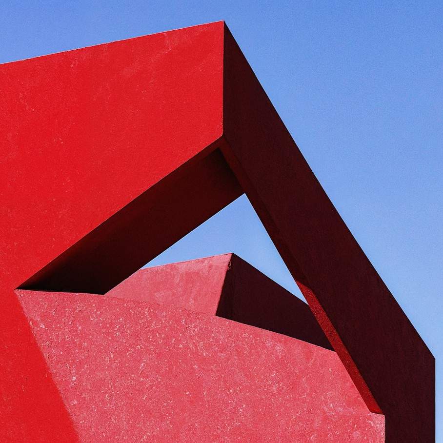 Close-up of bold red angular modern architecture against a clear blue sky.
