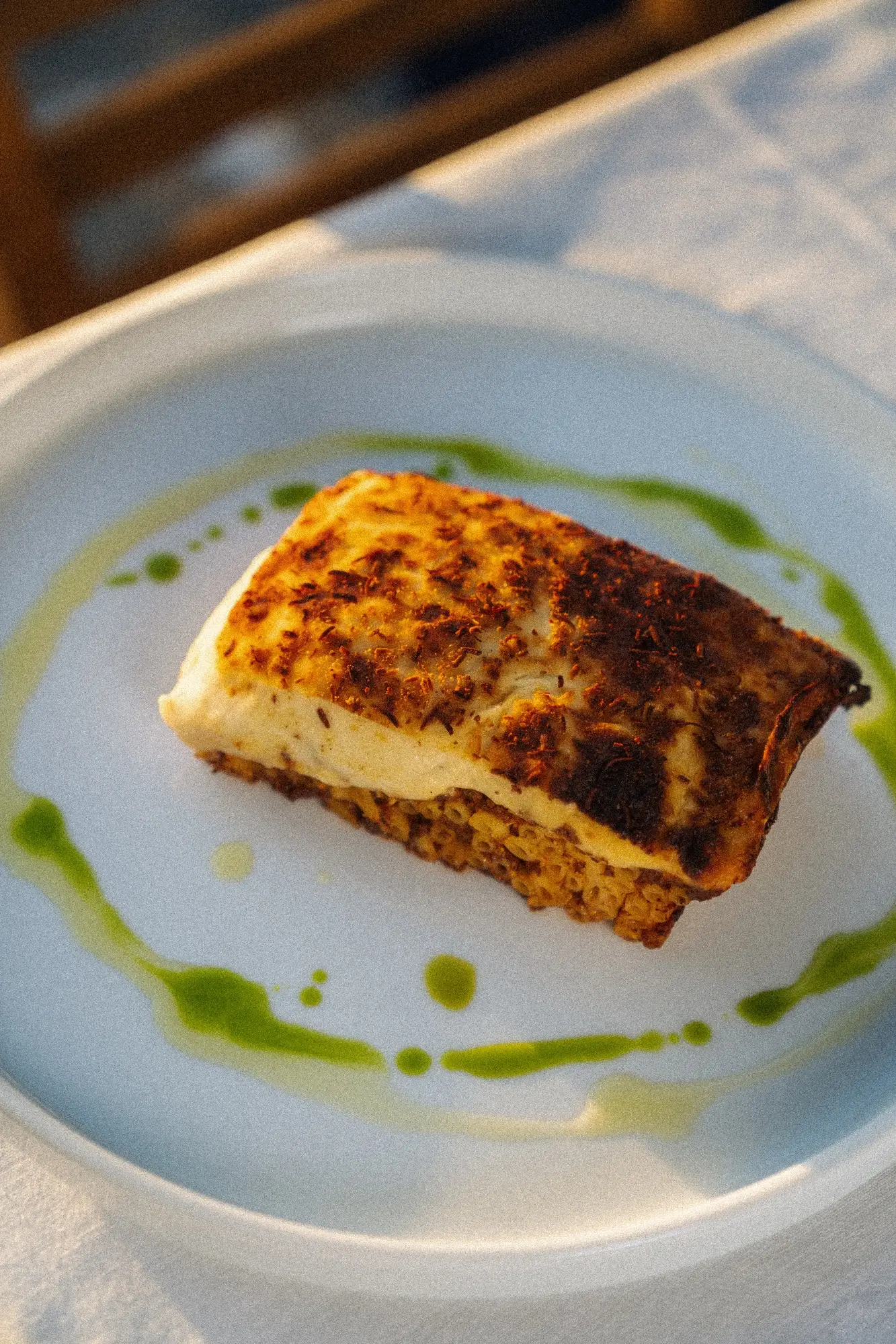 Grilled cheese slice with herb seasoning on a crispy base, served with a green sauce drizzle.