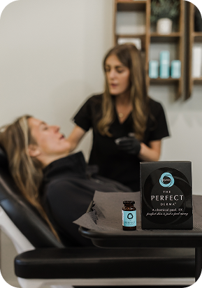 A skincare professional applies a facial peel to a reclining woman in a clinic setting.