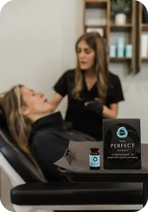A skincare professional applies a facial peel to a reclining woman in a clinic setting.