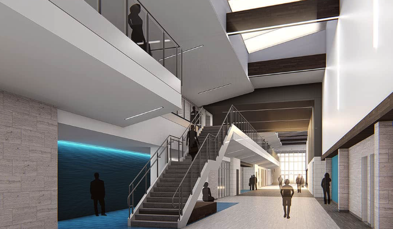 Modern open interior with a staircase, glass railings, and people walking in a spacious hallway.