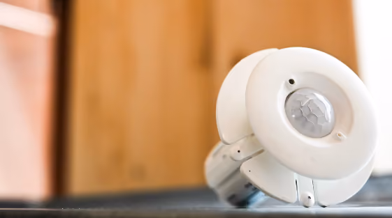 Close-up of a white smoke detector on a surface with a blurred wooden background.