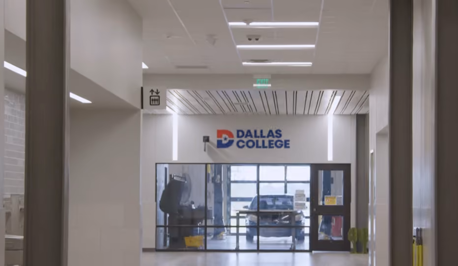 Interior hallway leading to a glass door entrance with a Dallas College logo above it.