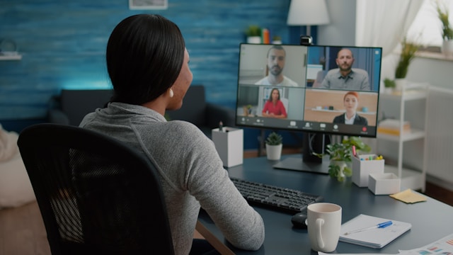 Woman attending a video conference with four colleagues on a computer in a home office.