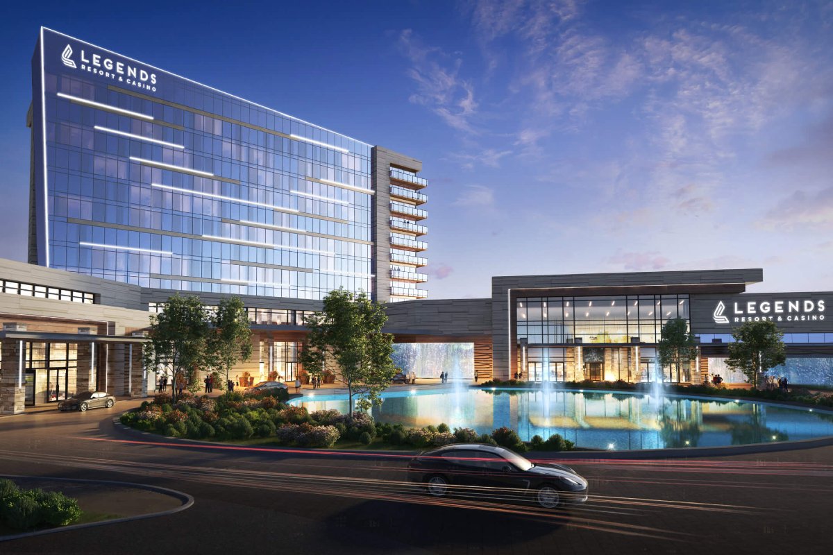 Legend Resorts & Casino building with glass facade, fountains, and cars at dusk.