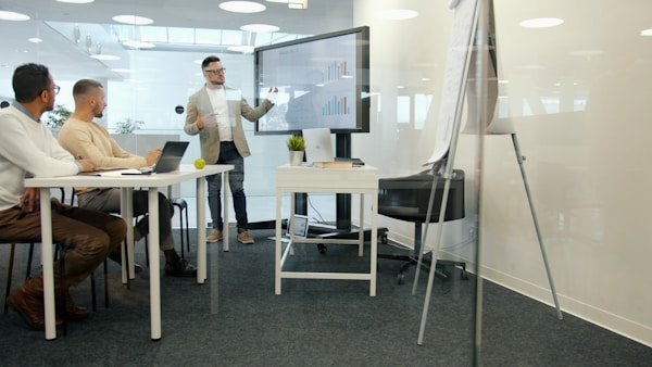 Employee reporting about sales results talking to staff in boardroom using digital screen with infographics explaining marketing strategy and finance.
