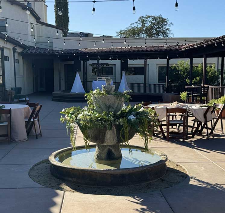 Tiered fountain dressed with greenery in the Villa La Paz courtyard set for an event under string lights