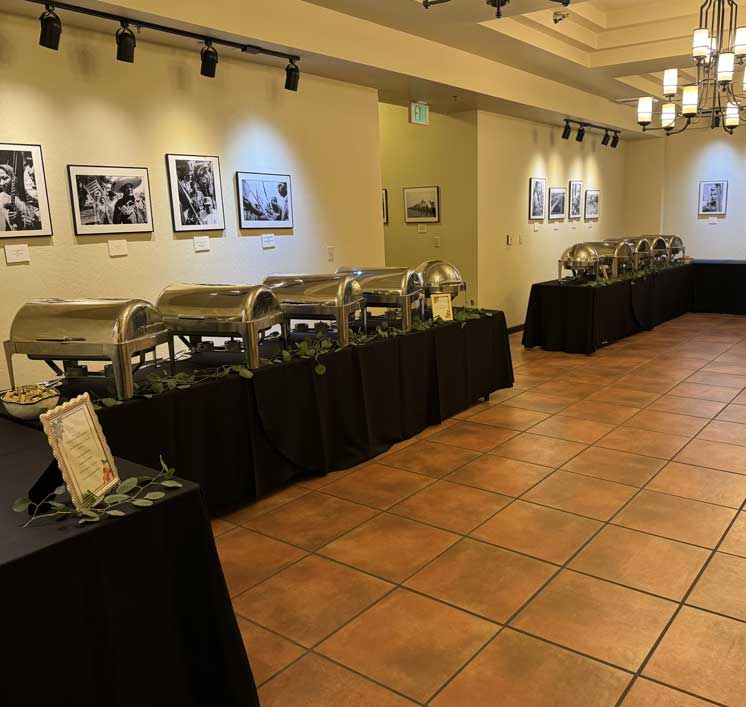 Buffet line of chafing dishes on black-draped tables in a gallery of black-and-white photographs