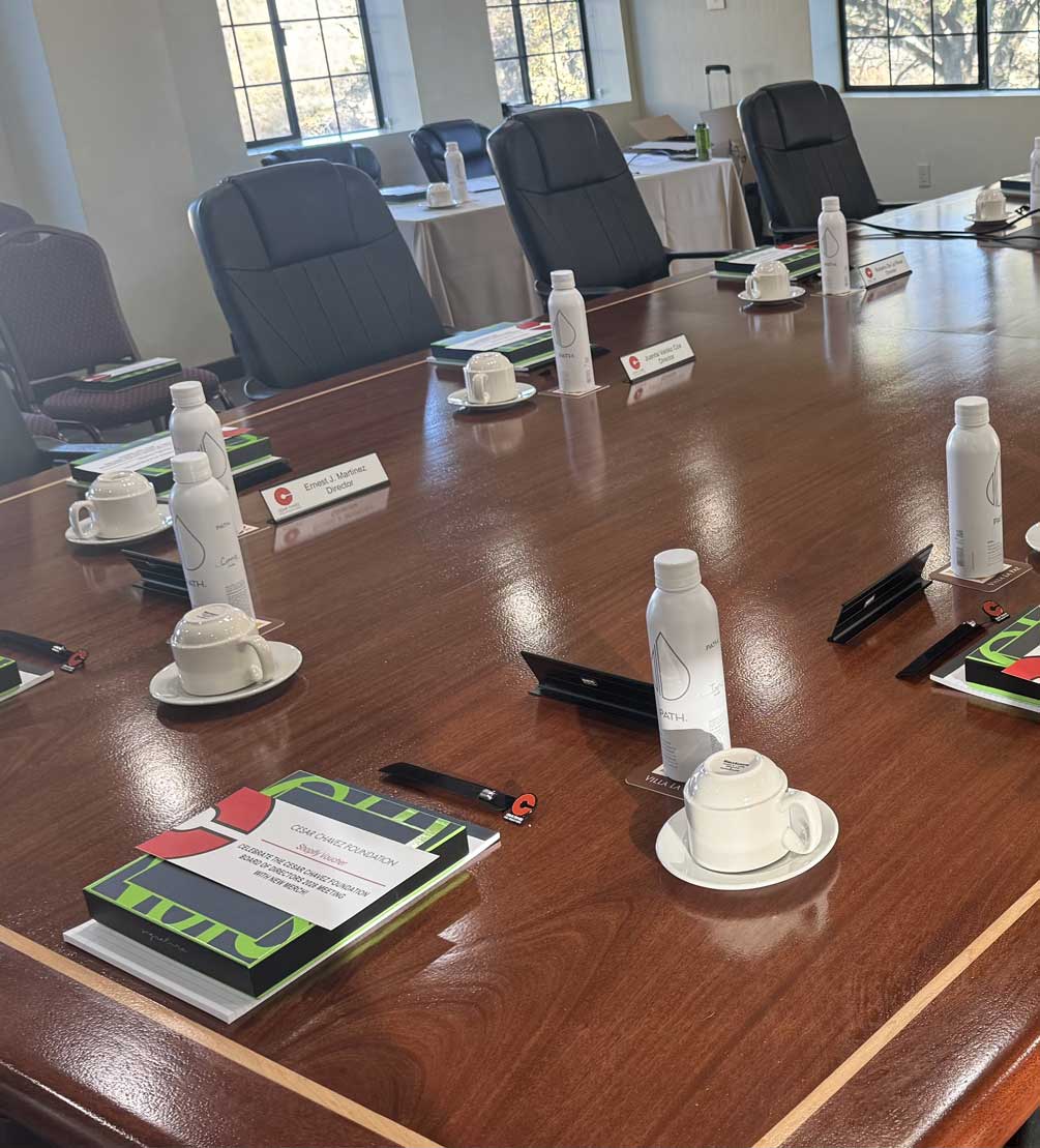 Wood boardroom table set for a meeting with leather chairs, notebooks, and coffee service