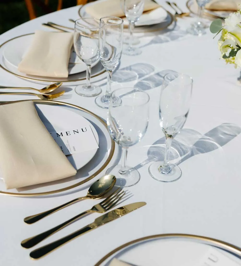 Elegant wedding table setting with gold-rimmed chargers, menu cards, and glassware