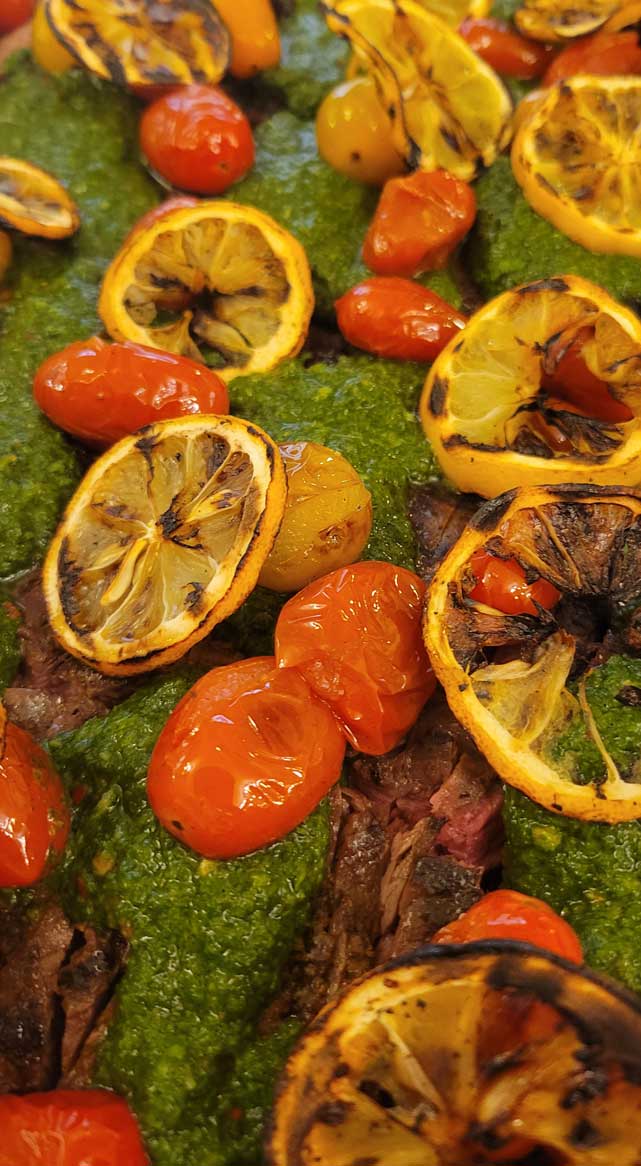 Roasted dish garnished with charred citrus slices and blistered tomatoes