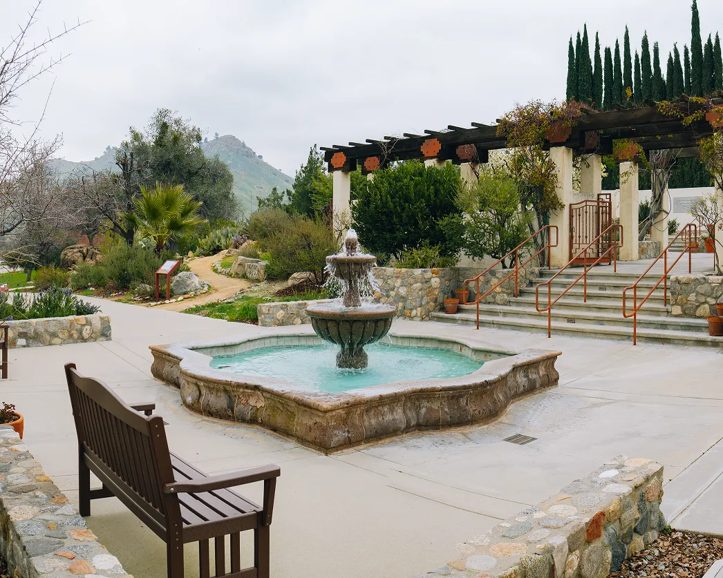 Stone fountain, garden bench, and pergola in the Villa La Paz courtyard with Tehachapi Mountain views