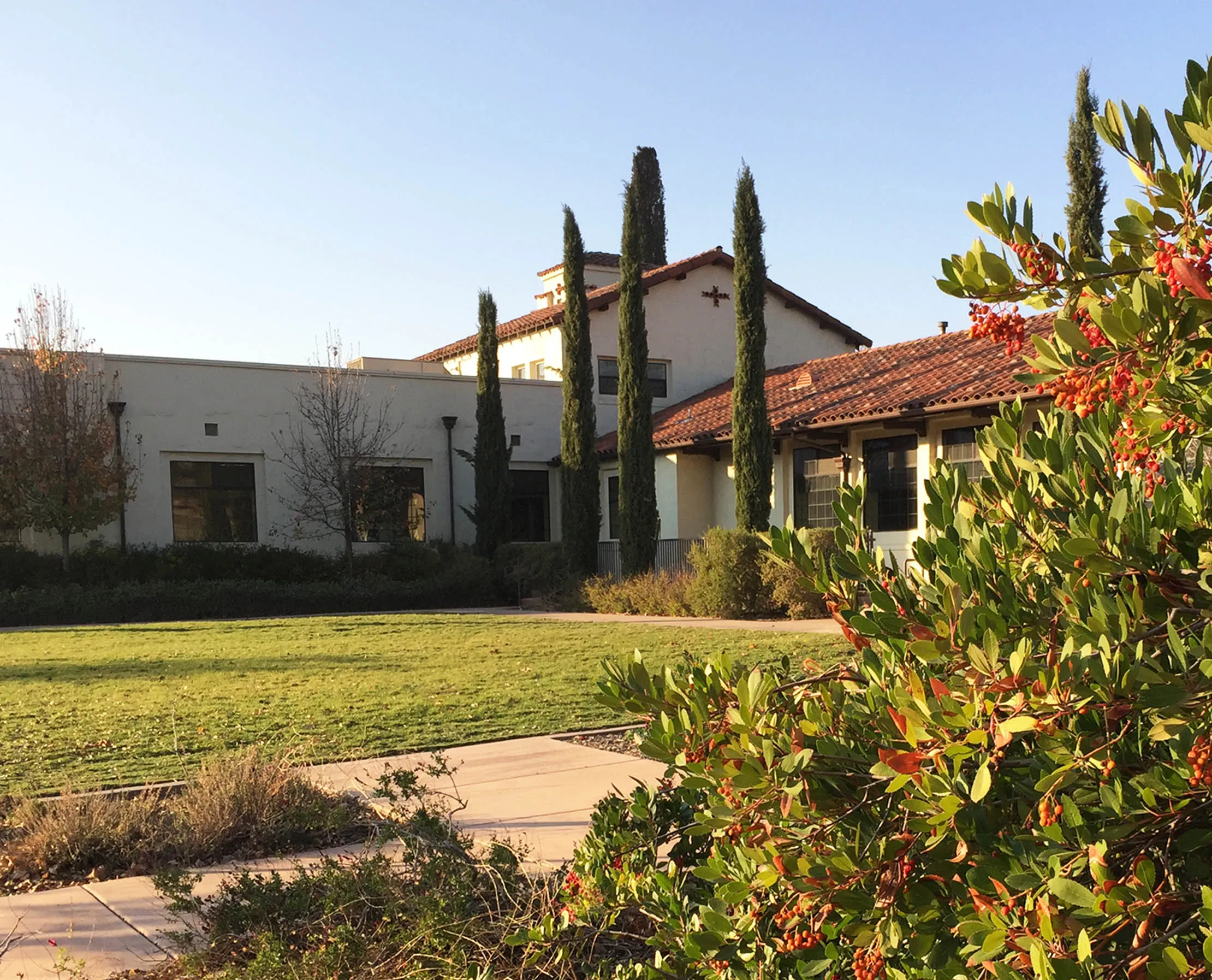 Villa La Paz mission-style building and lawn with red toyon berries in the foreground