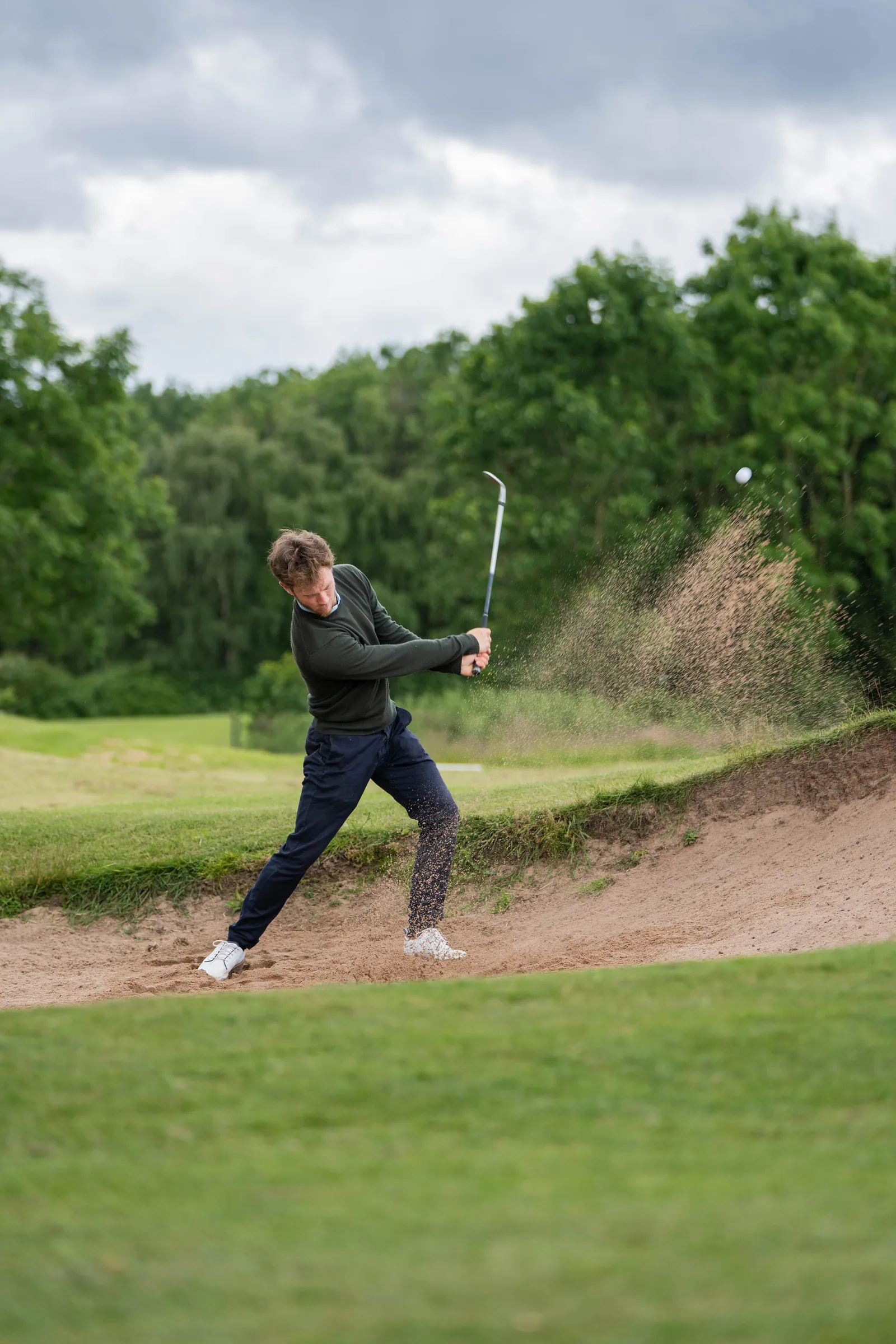 Player practising a bunker shot during a short game golf lesson in Derbyshire.