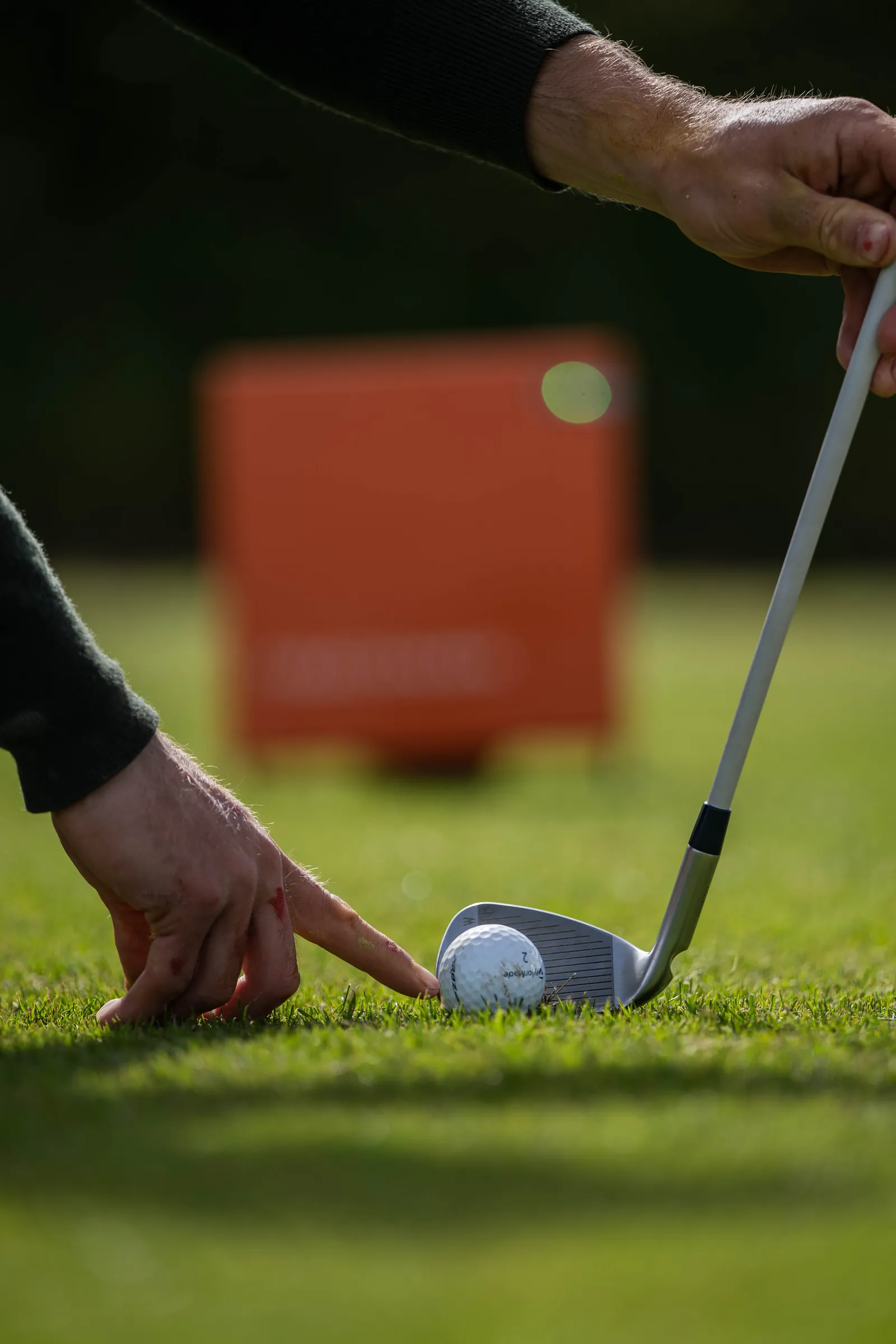 Driver club face aligned over a golf ball during a custom club fitting session.