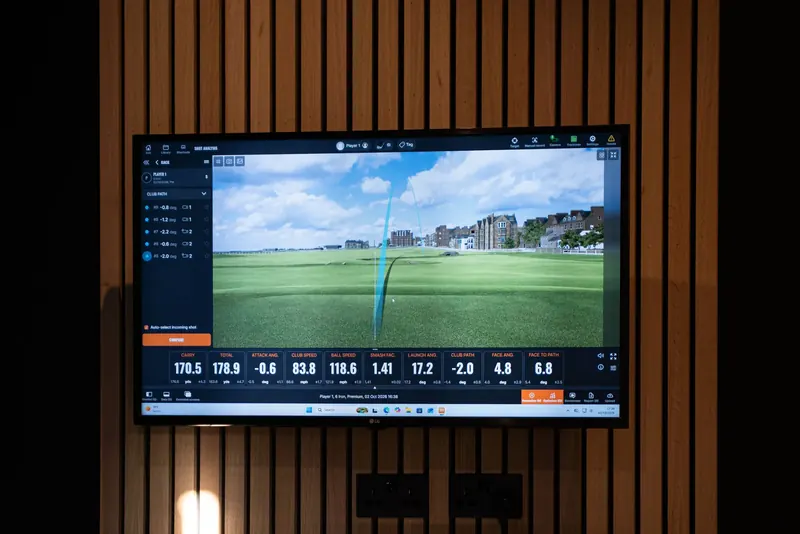 TrackMan screen on a slatted wall showing ball flight and launch data for golf lessons at Evolution Golf Academy in Derby.