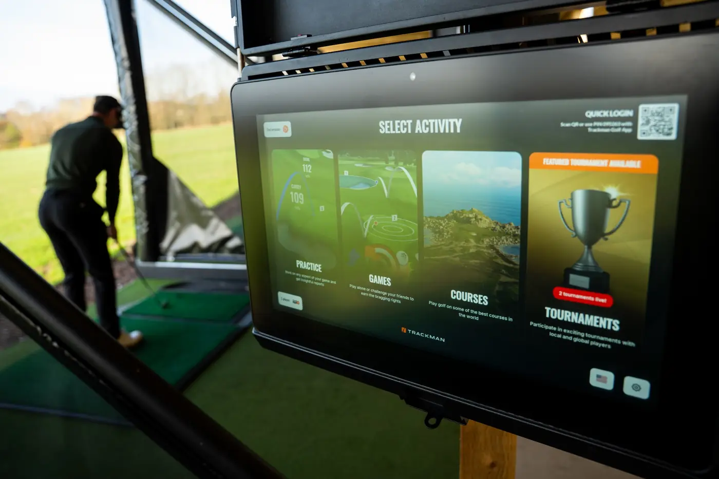 TrackMan driving range bay screen showing the Select Activity menu with a golfer hitting from a covered bay at Evolution Golf Academy near Derby