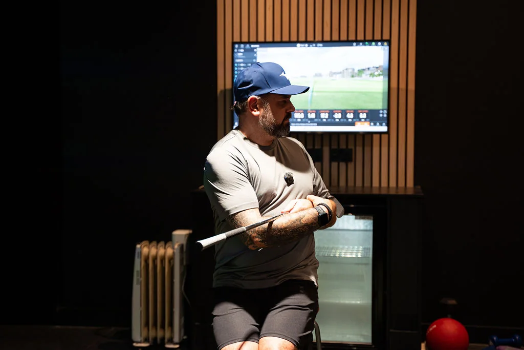Seated golfer turning the torso with a club across the shoulders during a TPI style screening at Evolution Golf Academy near Derby