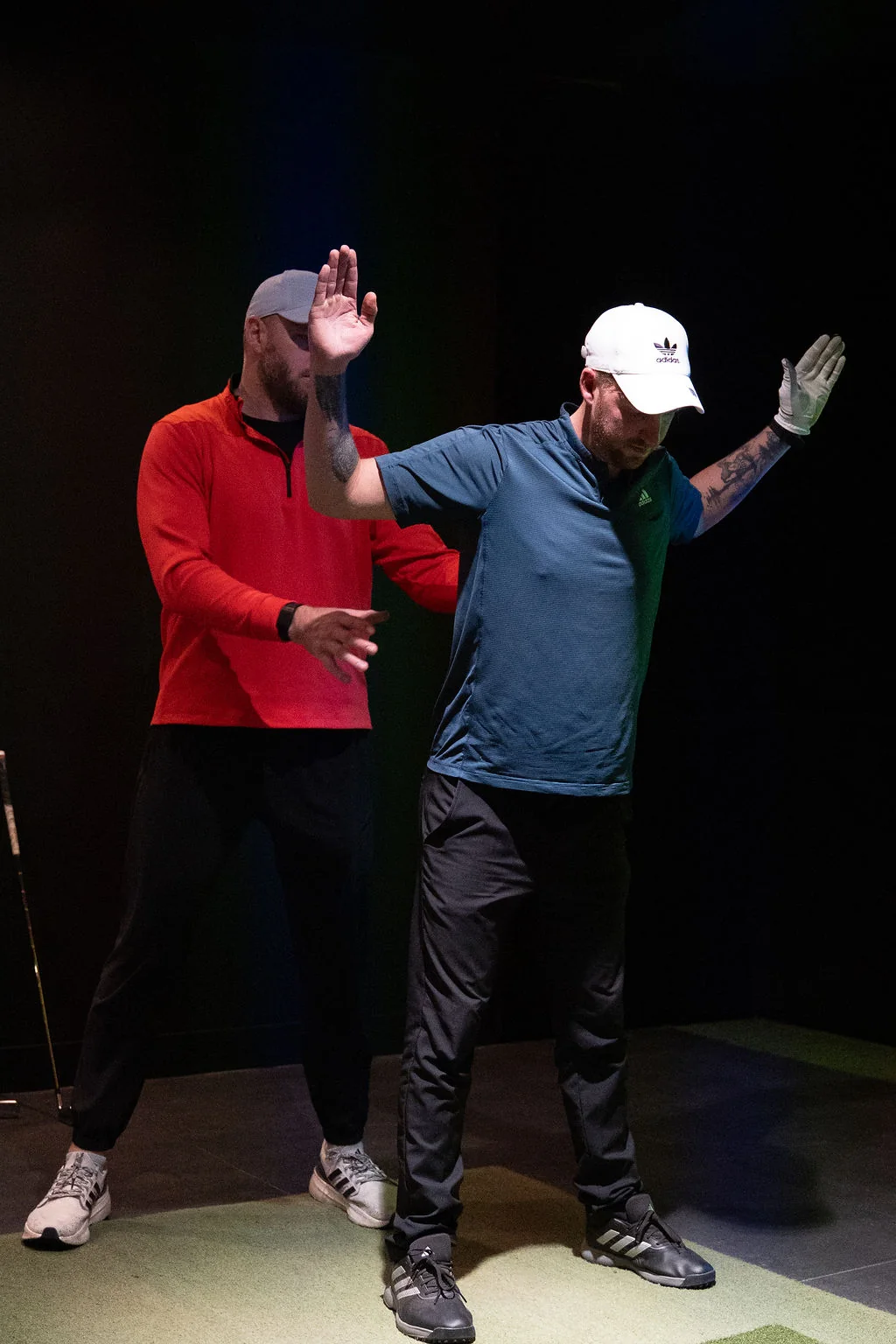 Golfer reaching one arm overhead during a shoulder reach test with the coach watching at Evolution Golf Academy near Derby