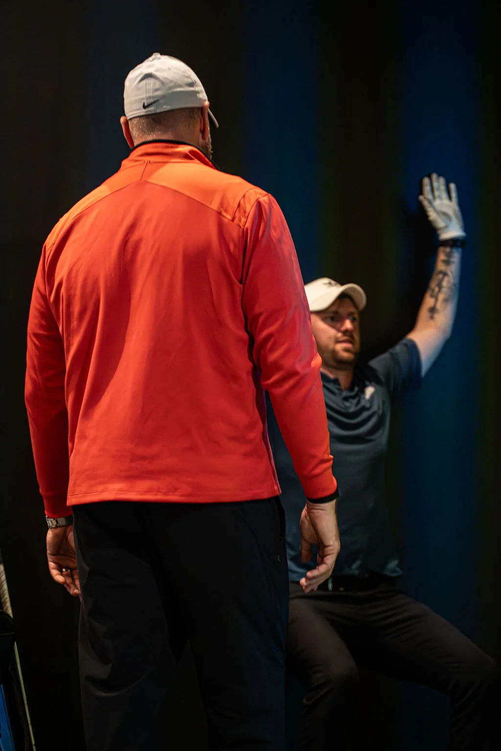 Coach watching a seated golfer raise one arm during a mobility assessment at Evolution Golf Academy near Derby