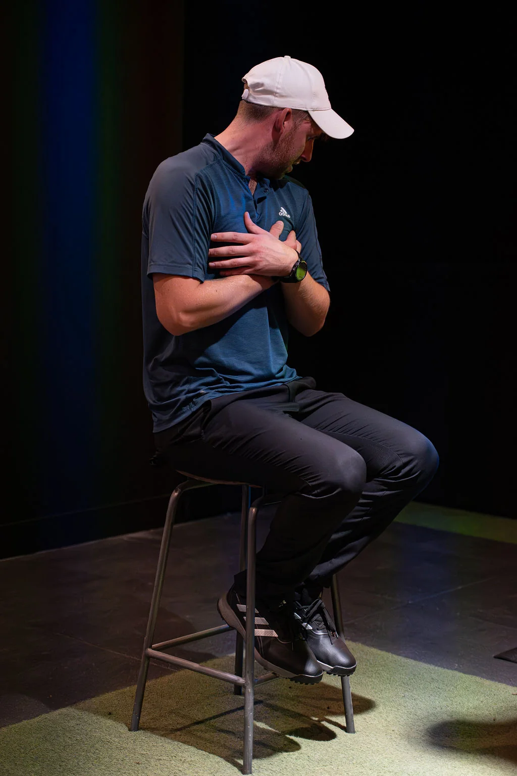 Golfer seated on a stool with a hand on the chest during a posture and breathing check at Evolution Golf Academy near Derby