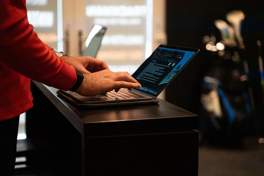 Coach typing screening notes into a laptop at the studio desk at Evolution Golf Academy near Derby