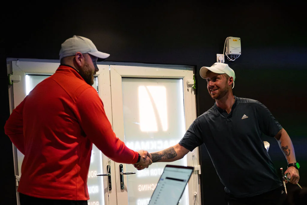 Coach and golfer shaking hands at the studio door at Evolution Golf Academy