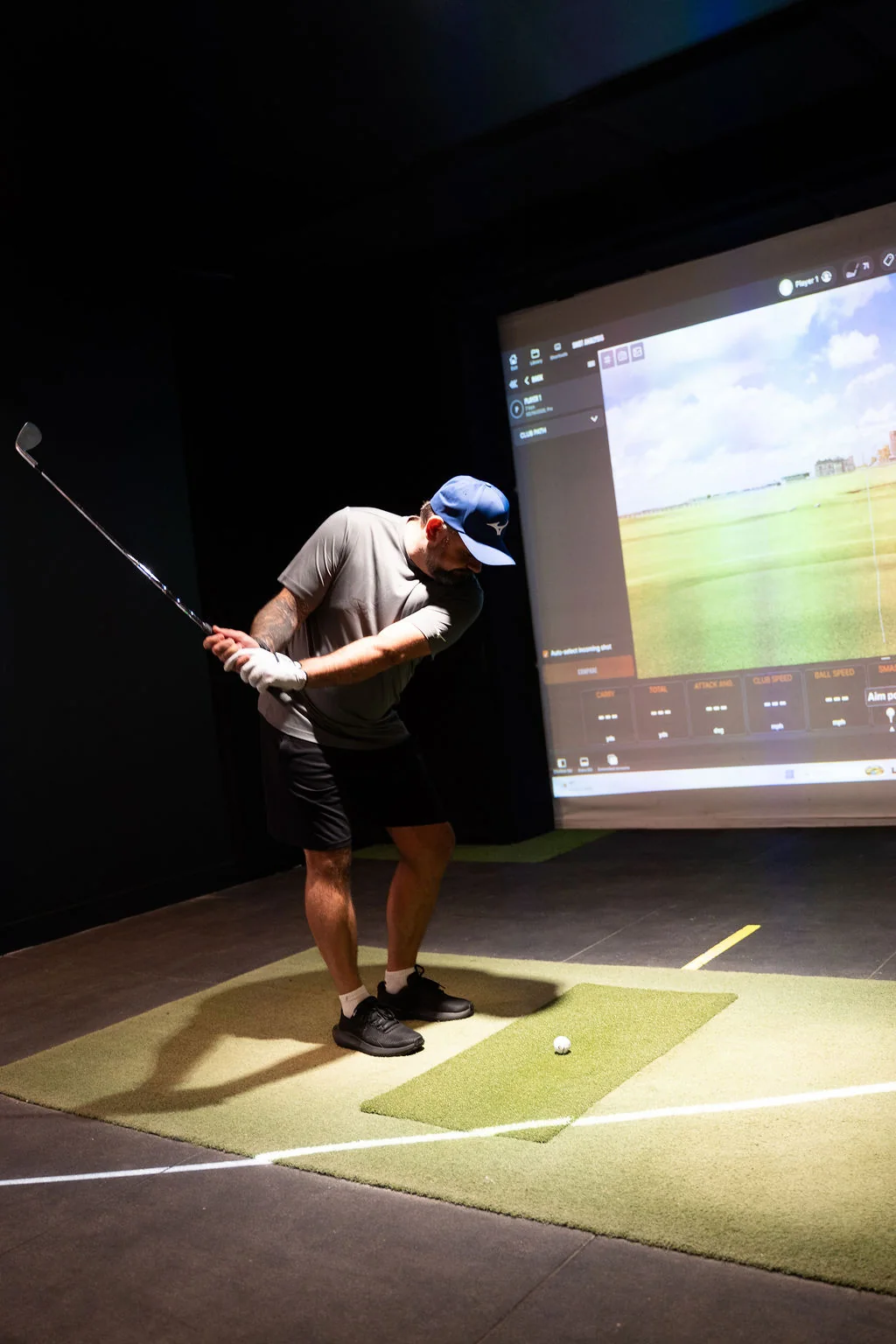Golfer in mid swing in the indoor simulator bay at Evolution Golf Academy