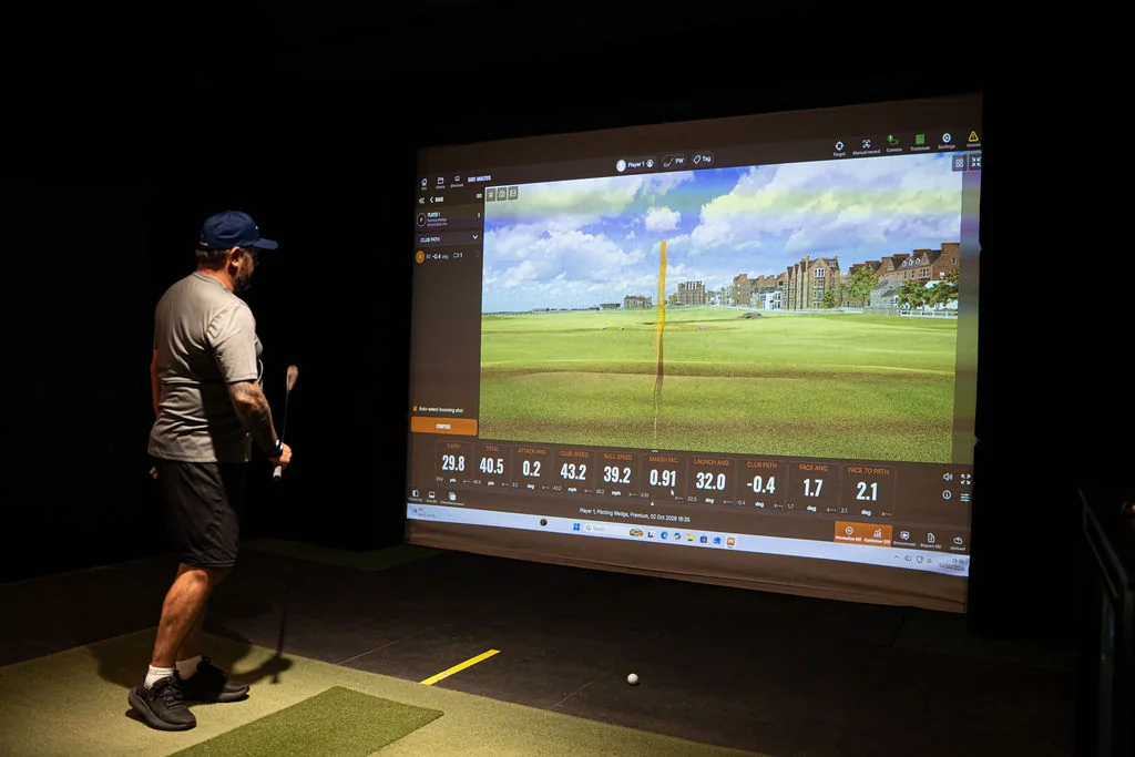 Golfer lining up a shot in front of the TrackMan simulator screen at Evolution Golf Academy near Derby