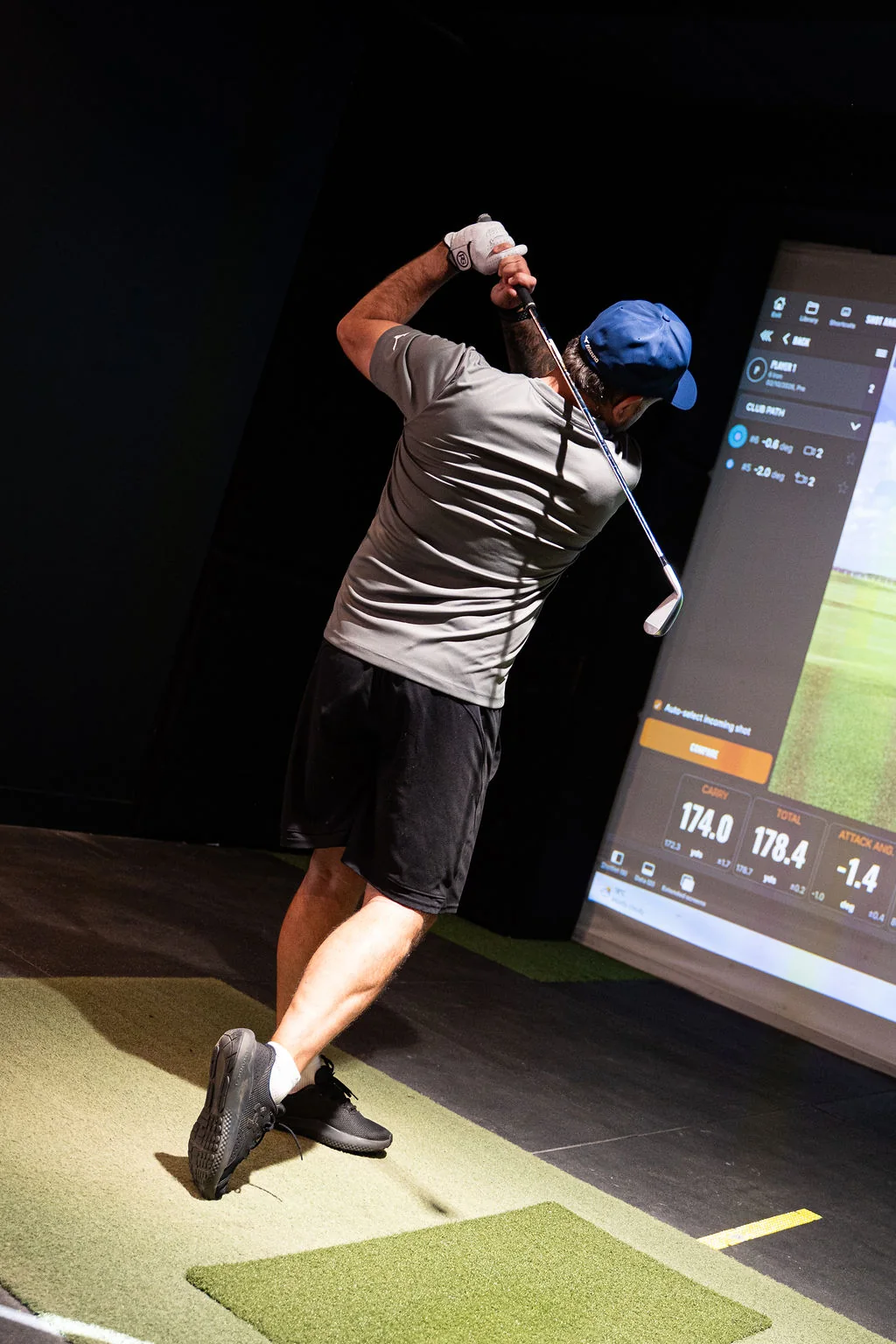 Golfer at the finish of a swing in front of the TrackMan simulator screen at Evolution Golf Academy near Derby