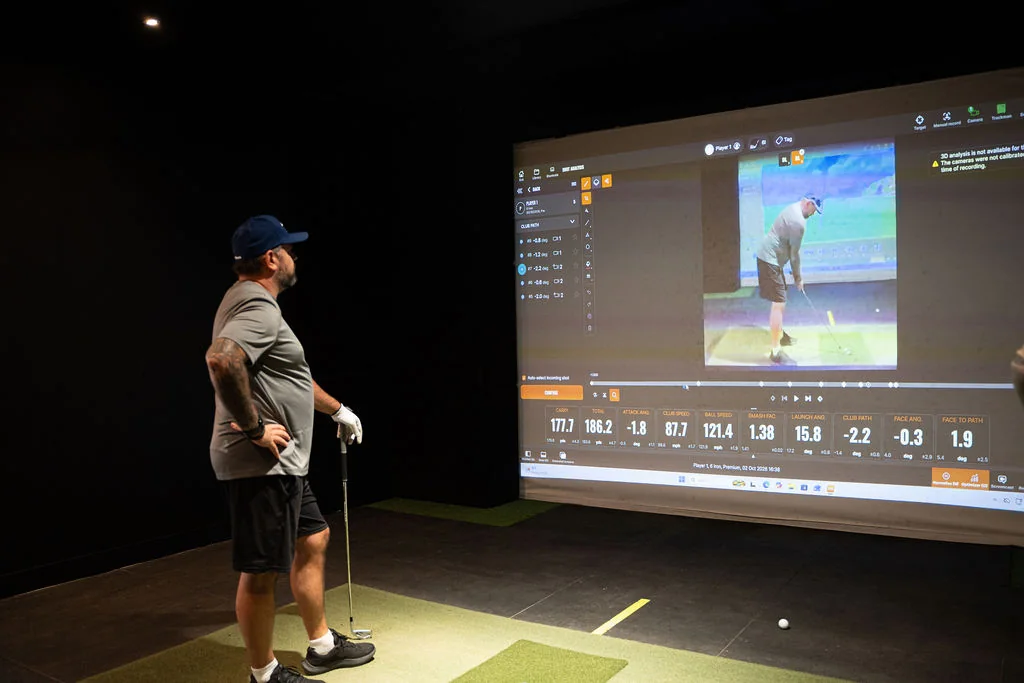 Golfer reviewing a swing replay beside the TrackMan simulator screen at Evolution Golf Academy near Derby