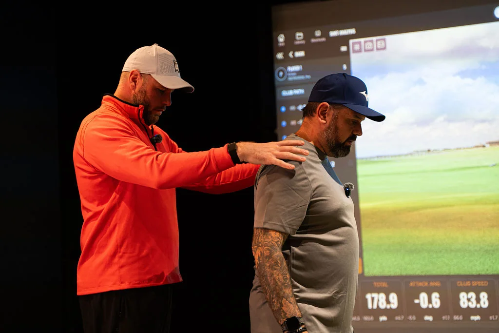Coach with a hand on a golfer's shoulder guiding the shoulder turn at Evolution Golf Academy near Derby